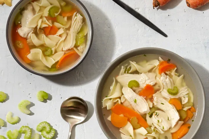 2 bowls of chicken soup with chopped vegetables