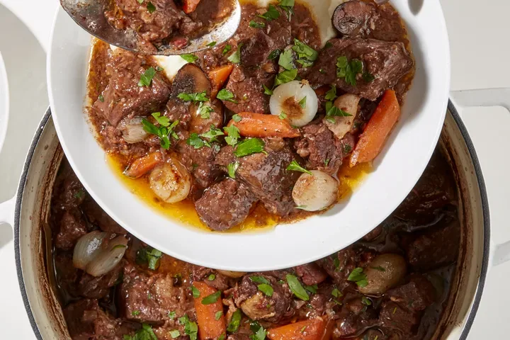 Beef bourguignon in pot spooned into dish